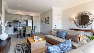 A modern living room with a sofa, coffee table, and a dining area with chairs and a table.