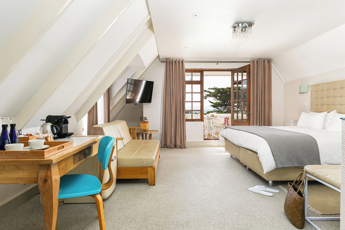 A hotel room with a bed, a desk with a chair, a television, and a view of the outdoors.