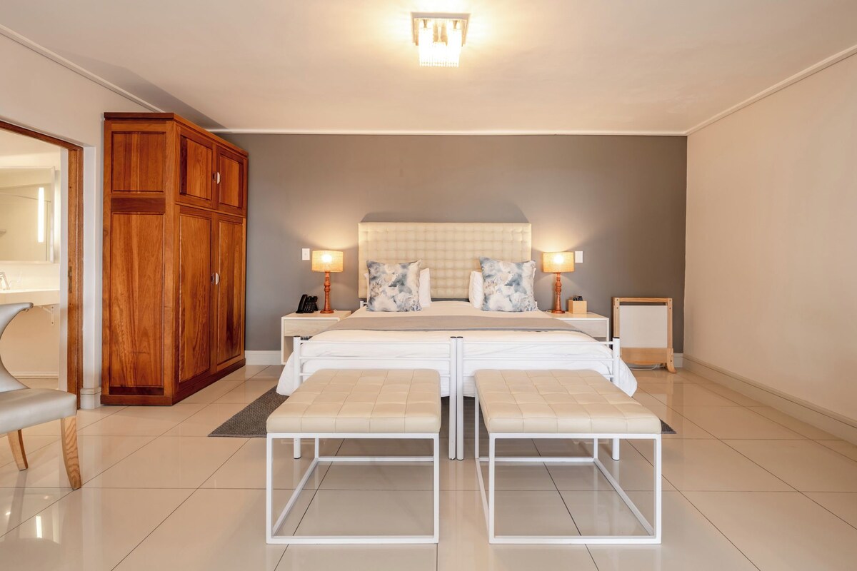 A bedroom with a double bed, bedside tables, a wardrobe, and a bench.