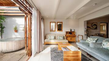 Amplia sala de estar con una mesa de centro de madera, un sofá y un ventanal con cortinas.