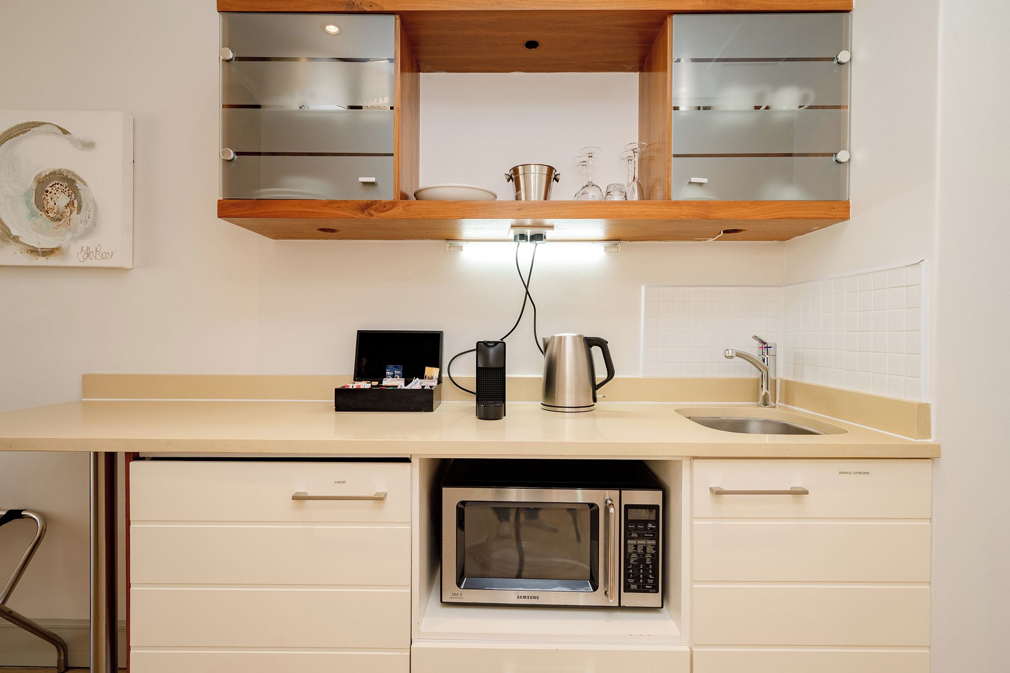 A kitchen with a microwave, kettle, and a coffee machine on the counter.