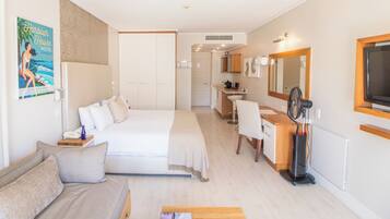 A hotel room with a bed, a sofa, a desk, a mirror, and a TV.