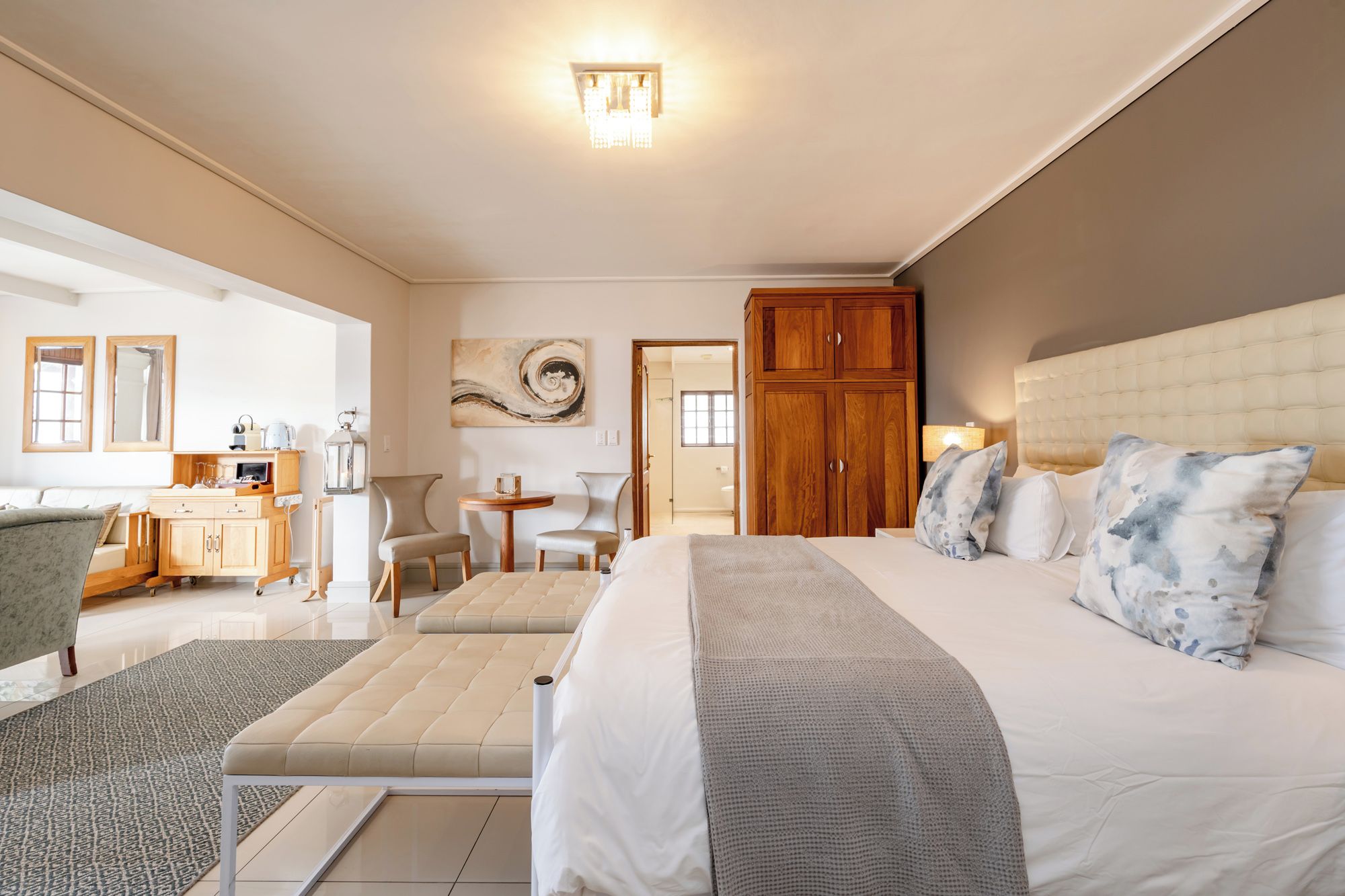 Una habitación de hotel con cama, escritorio, silla, sofá y un amplio armario de madera.