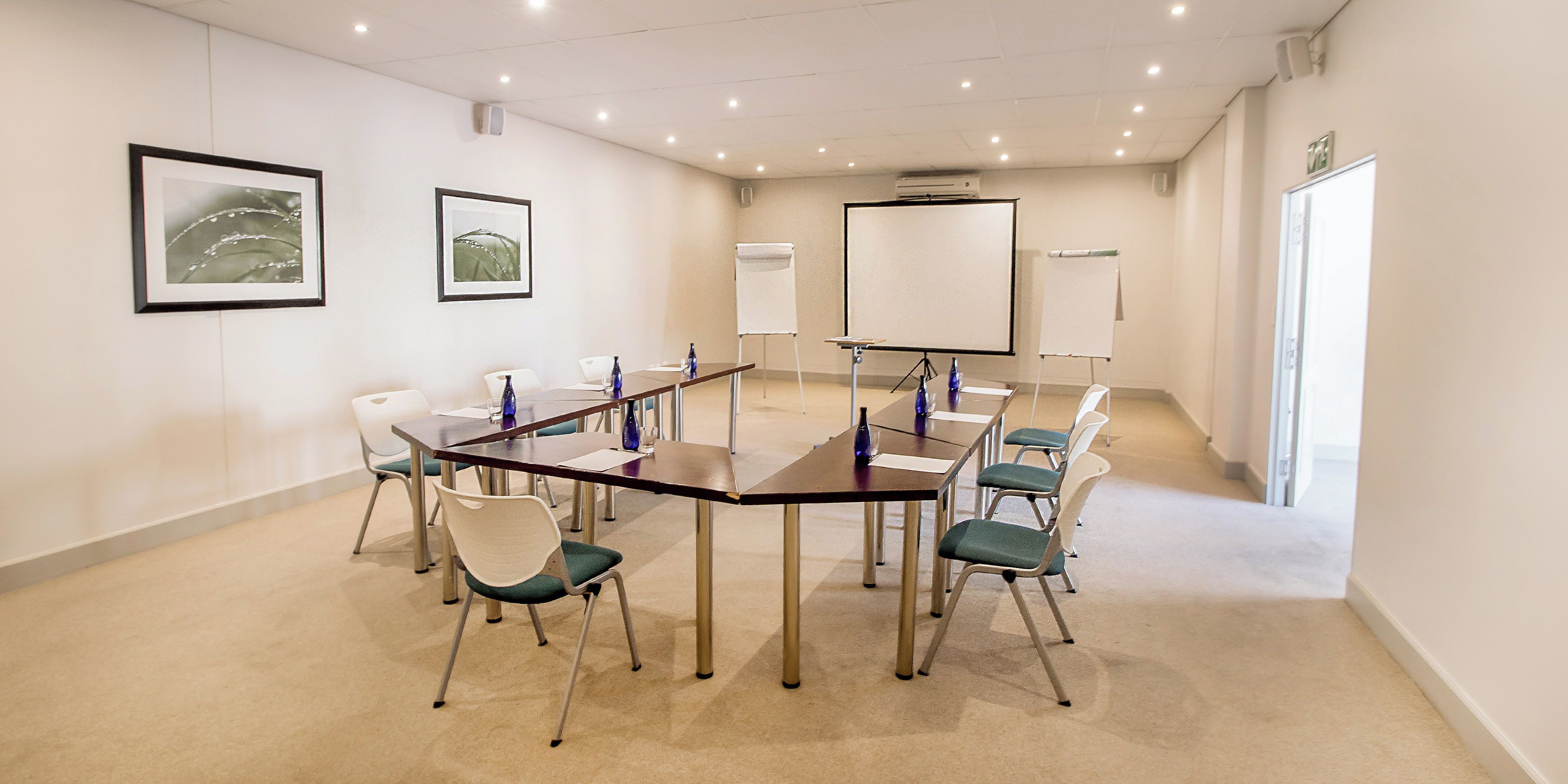 Uma sala de conferência com uma mesa comprida, cadeiras, um quadro branco e quadros nas paredes.