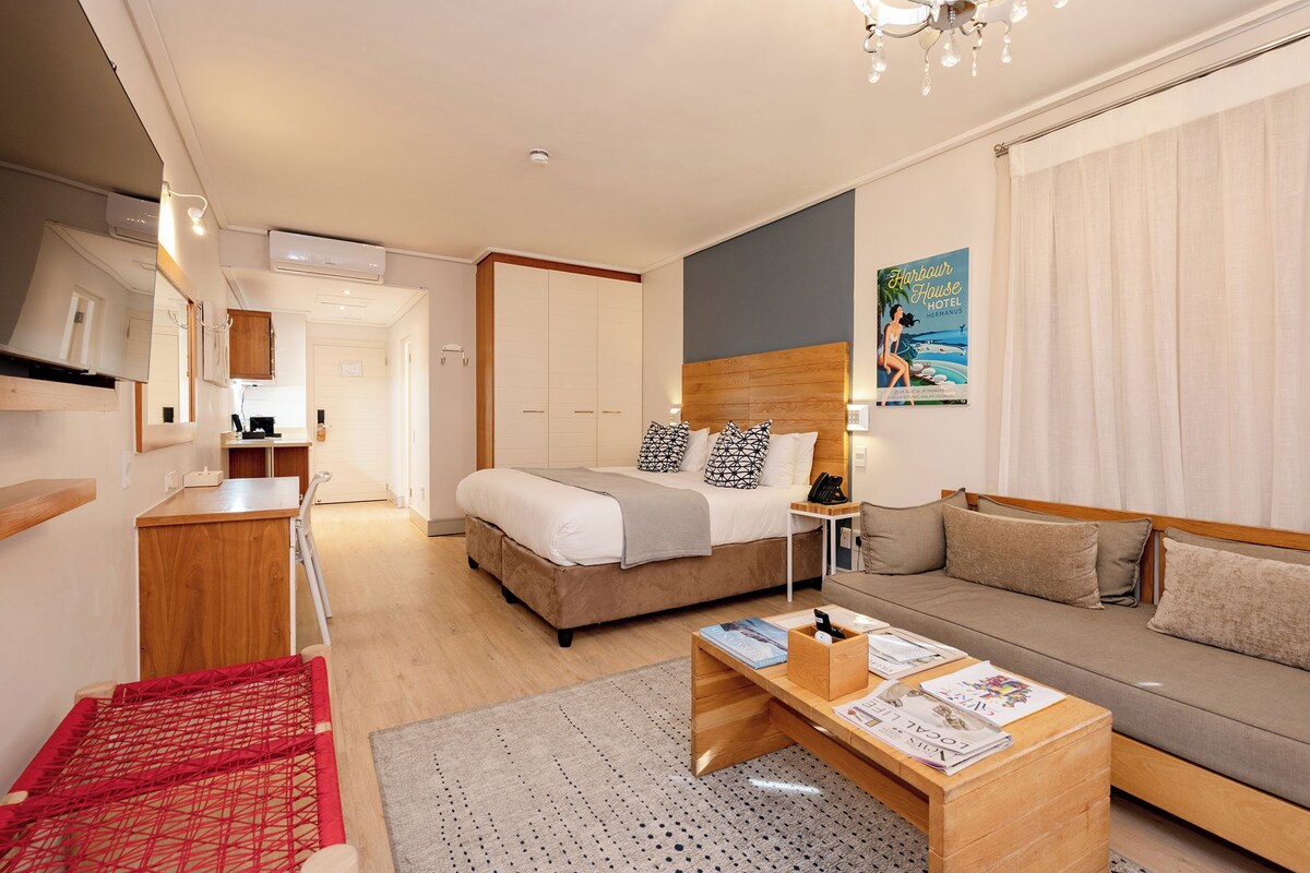 A hotel room with a bed, a sofa, a small desk, and a dining table.