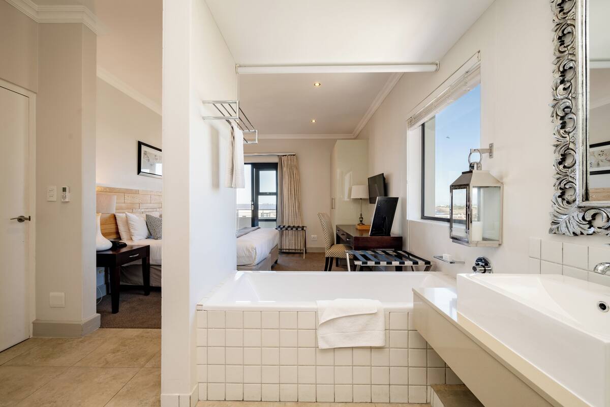 A modern hotel bathroom with a large bathtub, a separate shower area, and a vanity with a mirror.