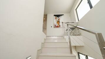 A modern staircase with a metal railing, leading to a room with a large abstract painting on the wall.
