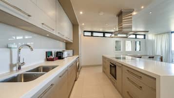 Una cocina moderna con electrodomésticos de acero inoxidable, horno empotrado y una isla grande con lavaplatos.