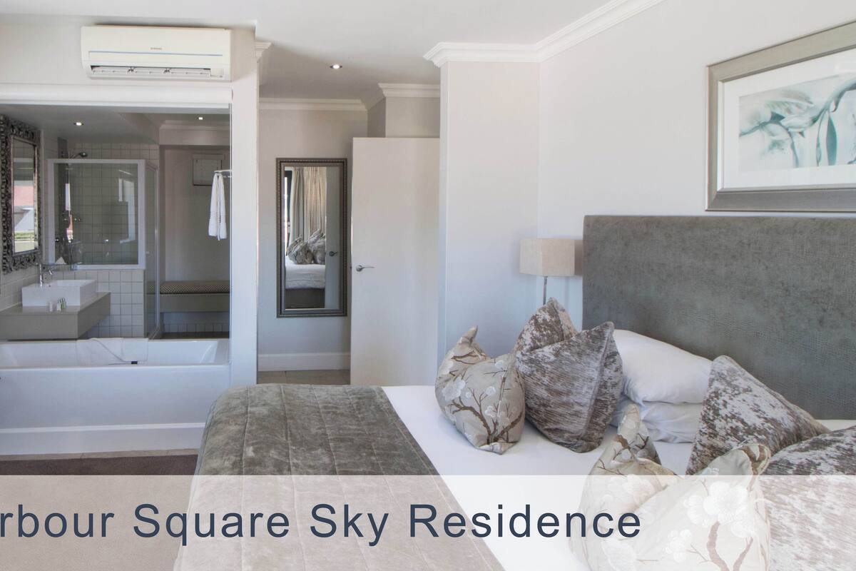 A modern hotel room with a large bed, a desk, a TV, a bathroom with a bathtub, and a shower.