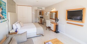A hotel room with a bed, a desk, a chair, a television, and a bathroom visible in the background.