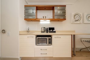 A compact kitchen with a built-in microwave, a kettle, and a coffee machine. - Harbour House Hotel (Hermanus)