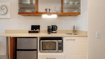 A compact kitchen with a built-in microwave, a coffee maker, and a small refrigerator.