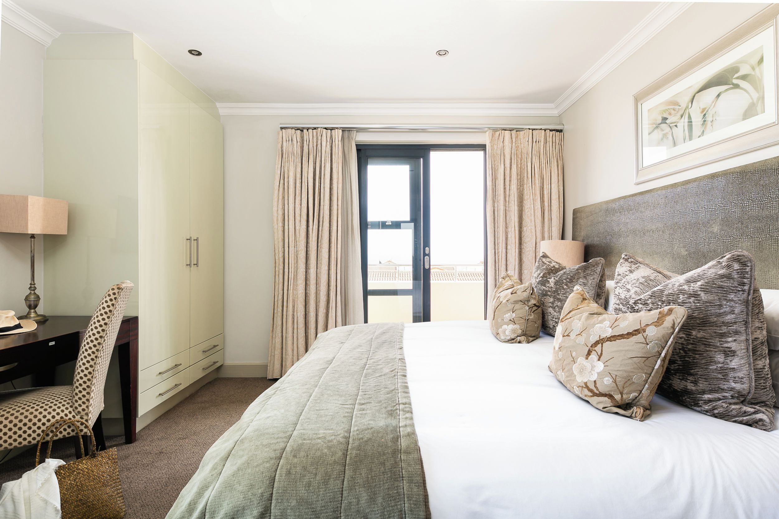 A hotel room with a bed, a desk, a chair, and a view of the outside.