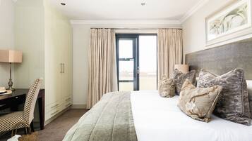 A hotel room with a bed, a desk, a chair, and a view of the outside.