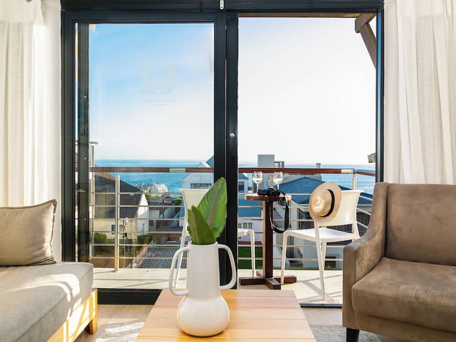 A balcony with a view of the sea, a white vase with a plant, and two sofas.