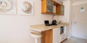 A kitchen with a countertop, a sink, and a cabinet. There are framed artworks on the wall.