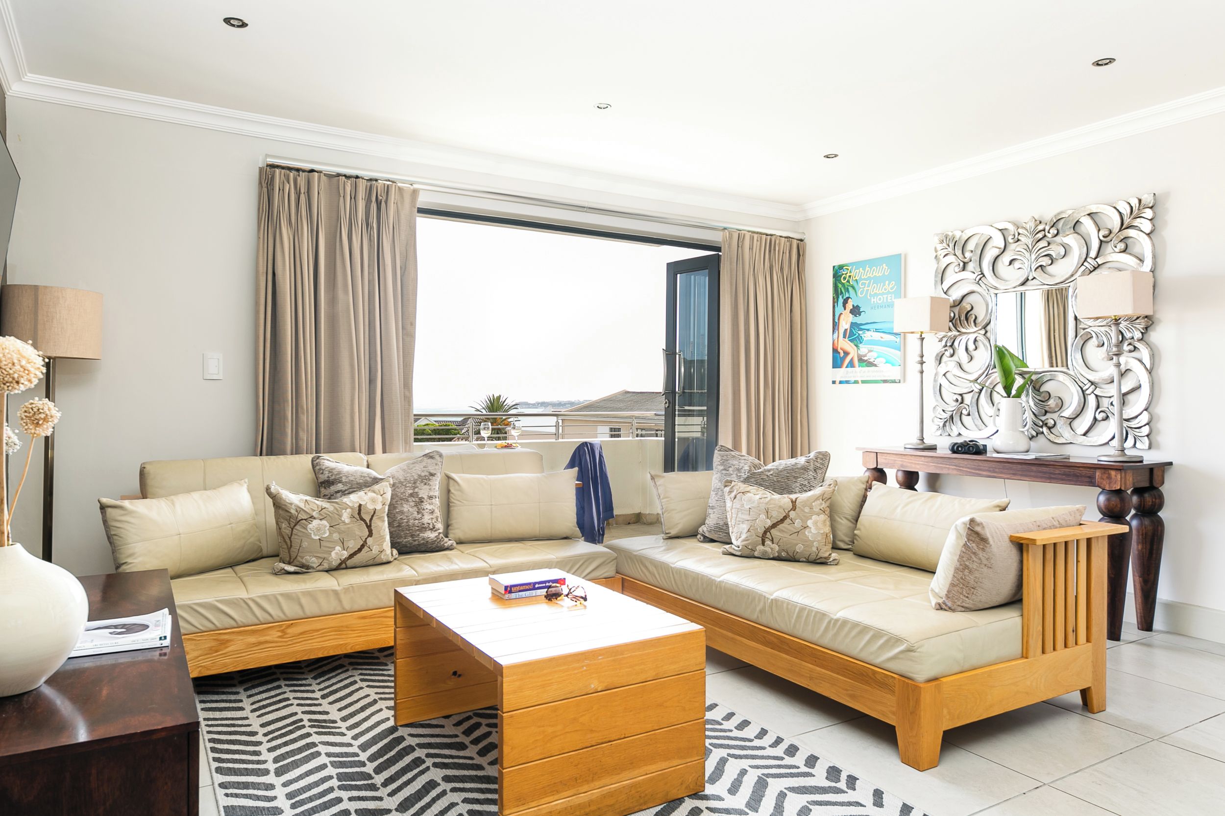 A modern living room with a sectional sofa, a wooden coffee table, and a large window with curtains.
