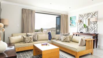 A modern living room with a sectional sofa, a wooden coffee table, and a large window with curtains.