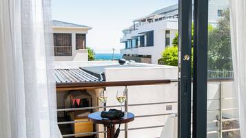 A balcony with a table, two glasses of white wine, and a camera.