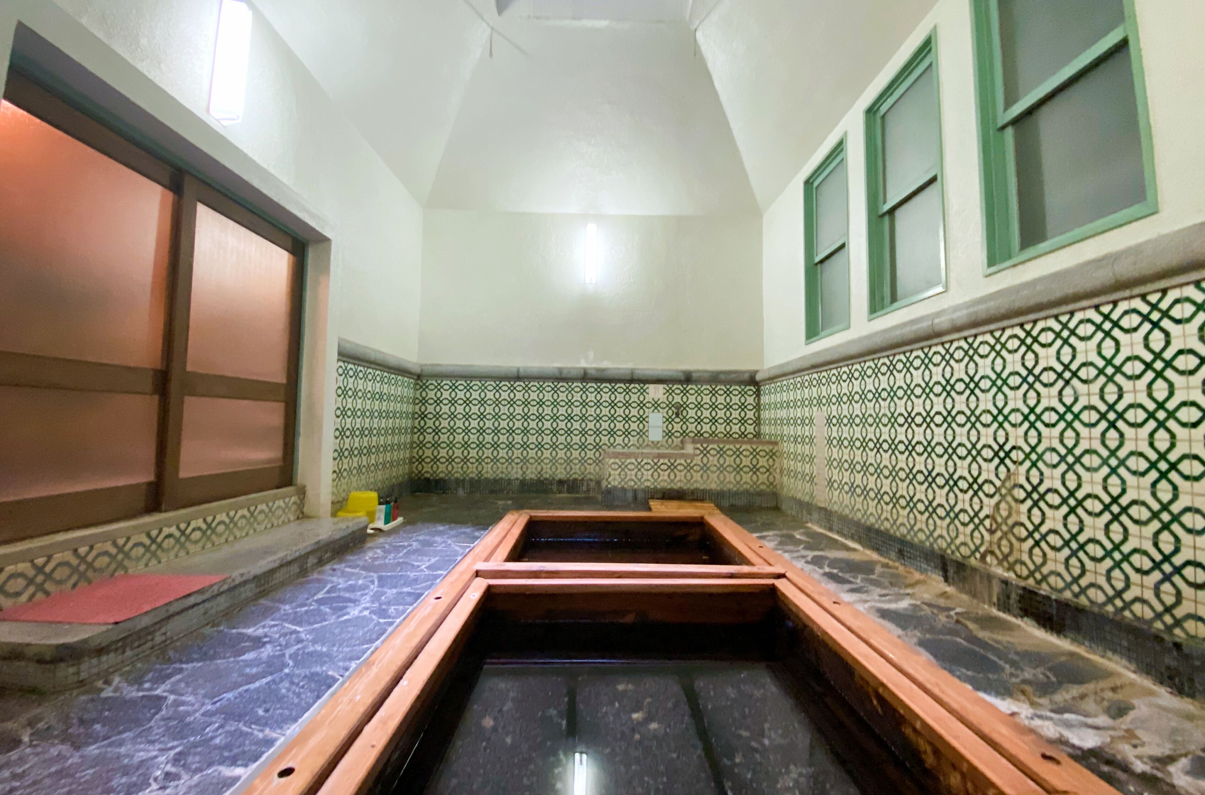 Um quarto com piso de azulejos, um banco de madeira e paredes estampadas.