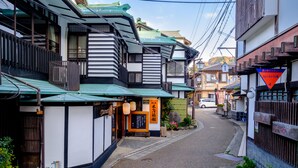 A narrow street with traditional Japanese buildings, a small shop with a sign, and a parked car. - Kiya Ryokan (Misasa)