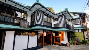 A traditional Japanese building with a wooden balcony, a green roof, and a sign with Japanese characters. - Kiya Ryokan (Misasa)