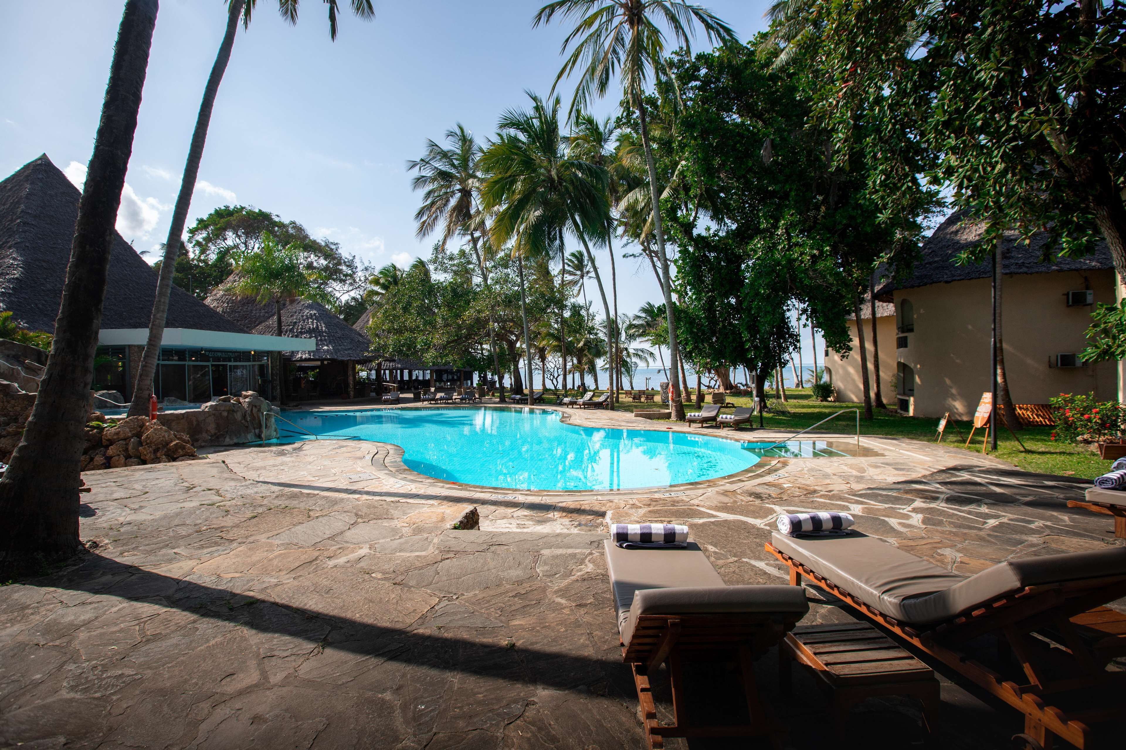 A swimming pool with lounge chairs and palm trees.