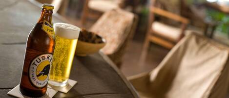 A bottle of Tusker beer and a glass of beer on a table in a restaurant setting.