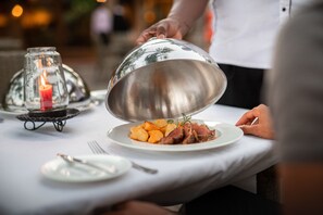 Una mesa de comedor con un plato de comida, una vela y una cúpula metálica.