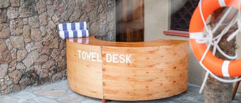 Escritorio de madera con toallas y la leyenda "TOWEL DESK" en un entorno hotelero.