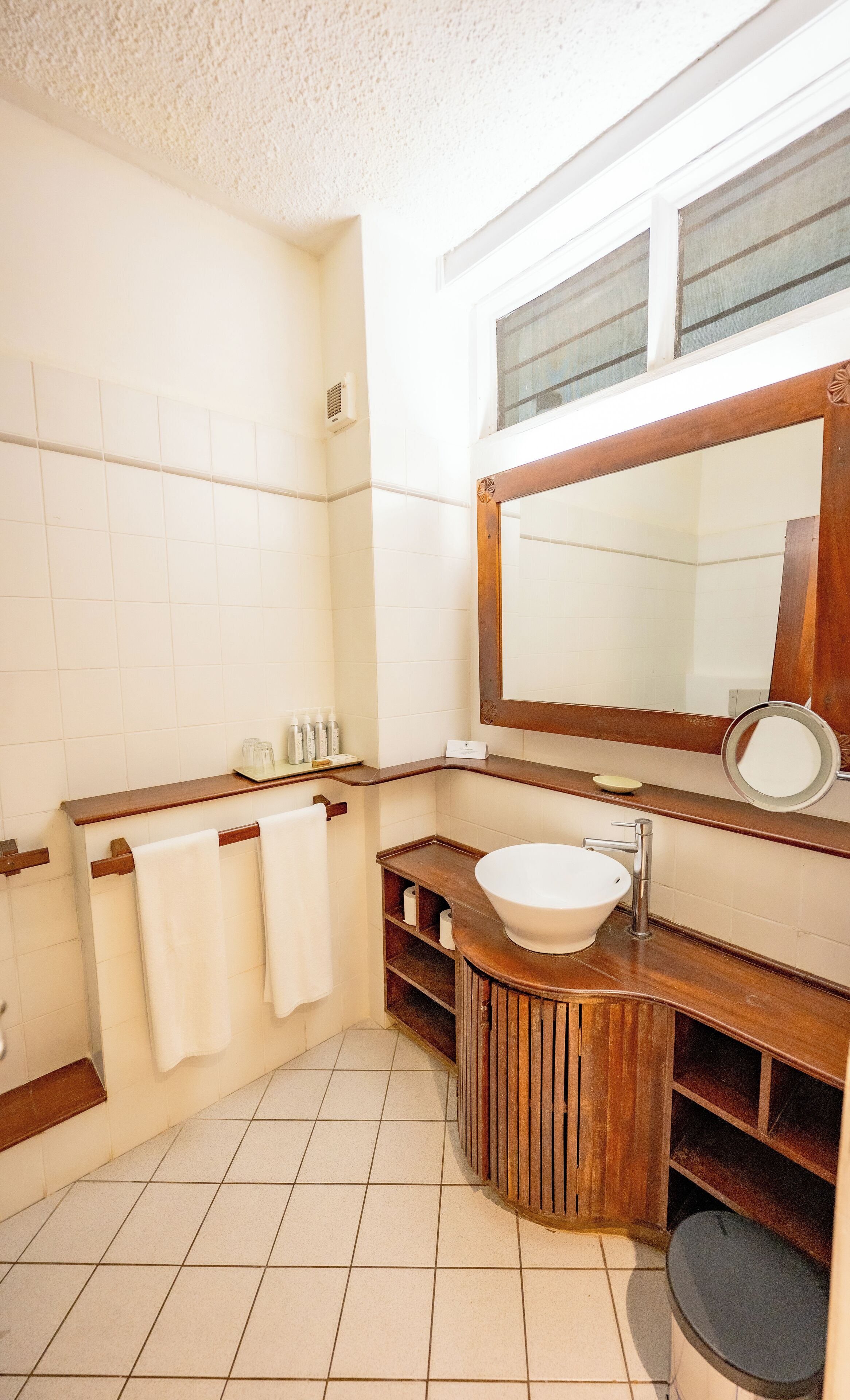 Een badkamer met een houten wastafelmeubel, een grote spiegel en een witte wasbak.