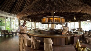 A bar area with a thatched roof, wooden furniture, and a circular bar counter. - Severin Sea Lodge (Mombasa)