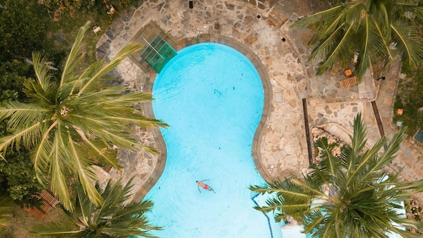An aerial view of a swimming pool surrounded by palm trees and stone pathways. - Severin Sea Lodge (Mombasa)