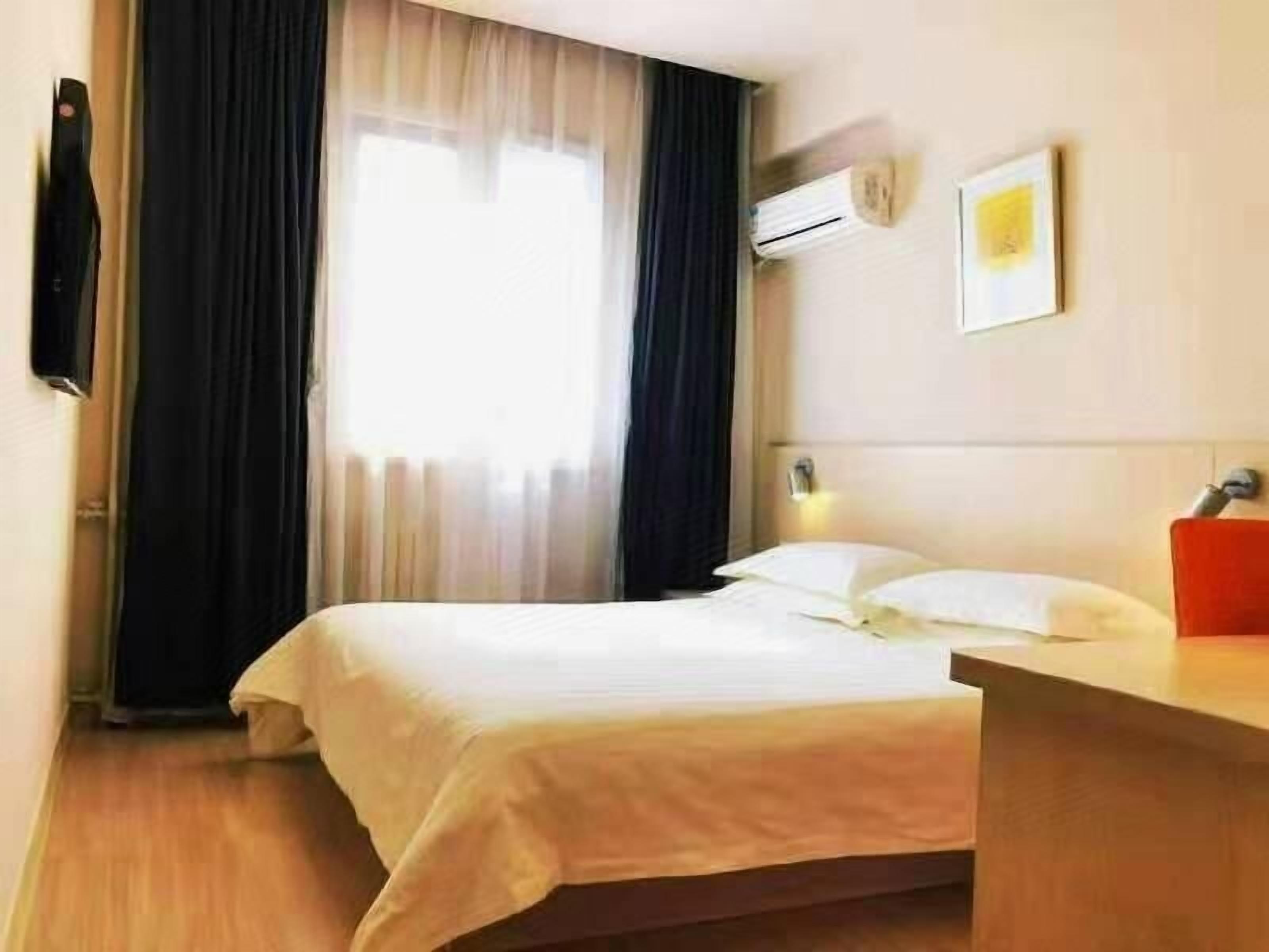 Ein Hotelzimmer mit Bett, Schreibtisch, Klimaanlage und einem fensterbepflanzten Fenster.
