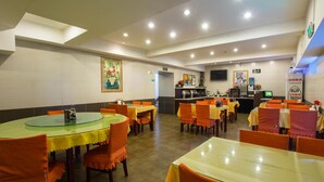 A restaurant with round tables and orange chairs, a counter with a menu, and a painting on the wall. - Jinjiang Inn (Beijing Tian'anmen Square Hepingmen Subway Station) (Beijing)