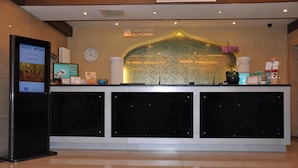 A hotel reception desk with a digital screen, a clock, and a decorative wall. - Jinjiang Inn (Beijing Tian'anmen Square Hepingmen Subway Station) (Beijing)