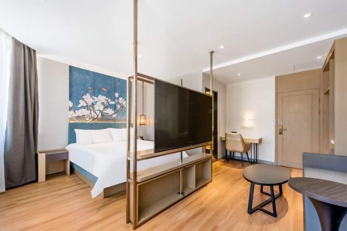 Ein modernes Hotelzimmer mit Bett, Fernseher, Schreibtisch und Stuhl.