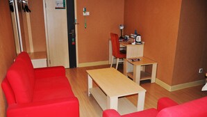 A room with a red sofa, a wooden coffee table, a small desk with a chair, and a door with a handle. - Jinjiang Inn (Beijing Tian'anmen Square Hepingmen Subway Station) (Beijing)