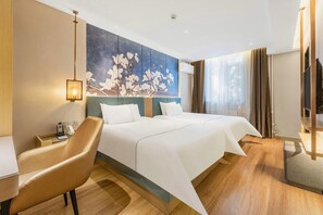 Ein Hotelzimmer mit zwei Betten, einem Schreibtisch, einem Stuhl, einem Bild an der Wand und einem Fernseher.