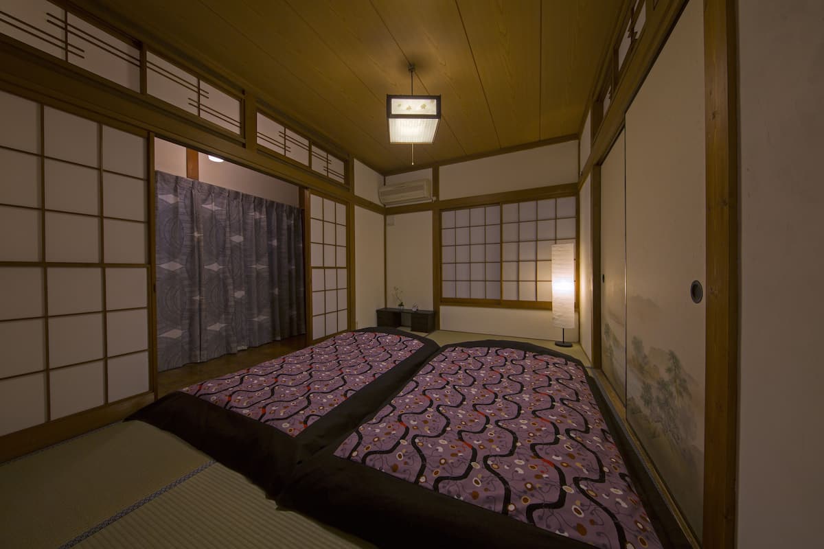 A traditional Japanese room with tatami flooring, shoji screens, and a futon bed.
