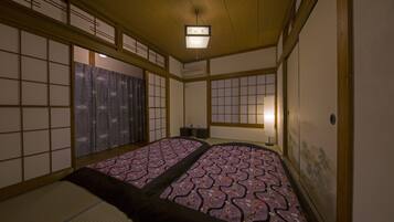 Une pièce de style japonais traditionnel, avec un sol recouvert de tatamis, des paravents en papier de riz (shoji) et un futon servant de lit.