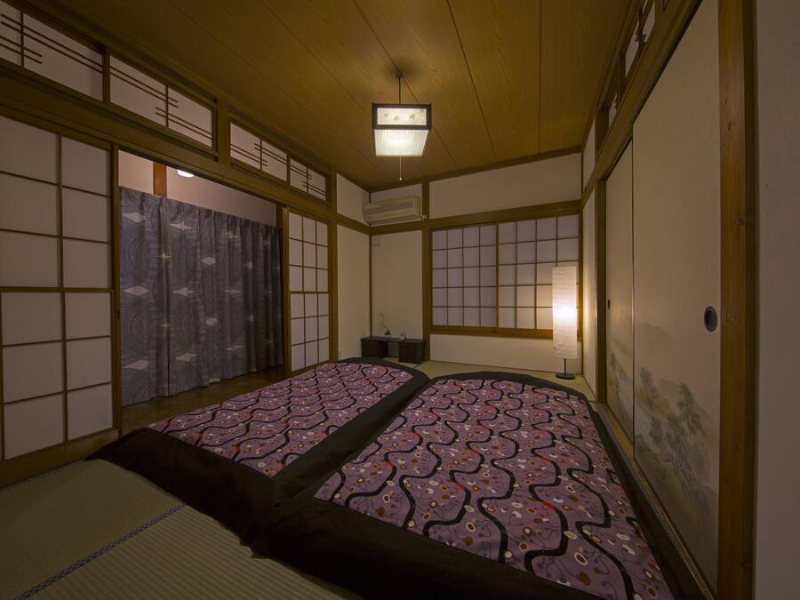 Une pièce de style japonais traditionnel, avec un sol recouvert de tatamis, des paravents en papier de riz (shoji) et un futon servant de lit.