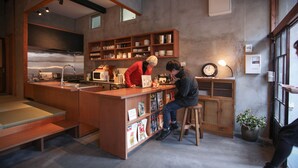 A modern kitchen with a central island, wooden cabinets, and a clock on the wall. - Sheena and Ippei - Hostel (Tokyo)
