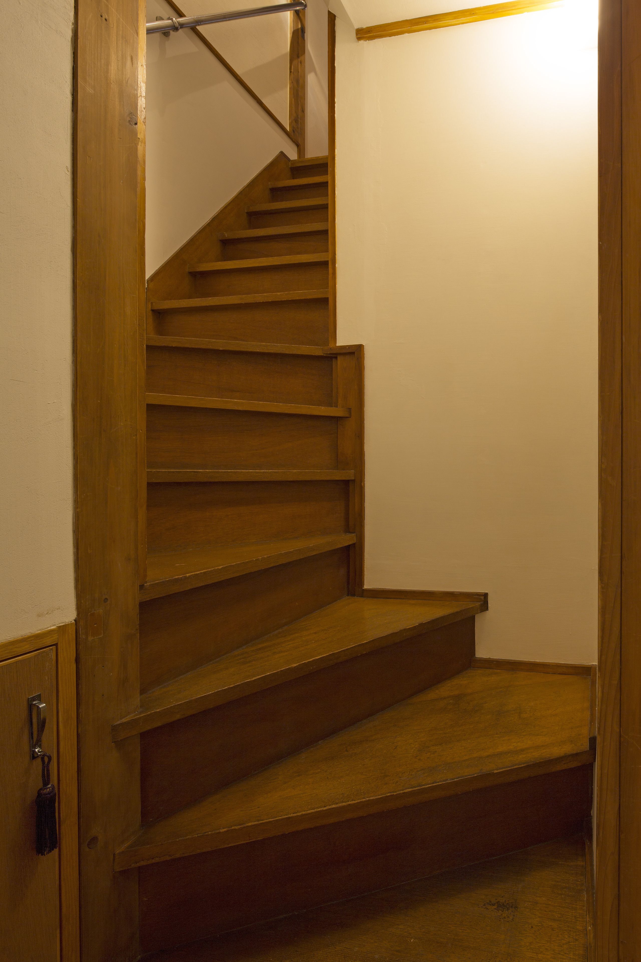 A wooden staircase with a metal handrail, leading to a landing.