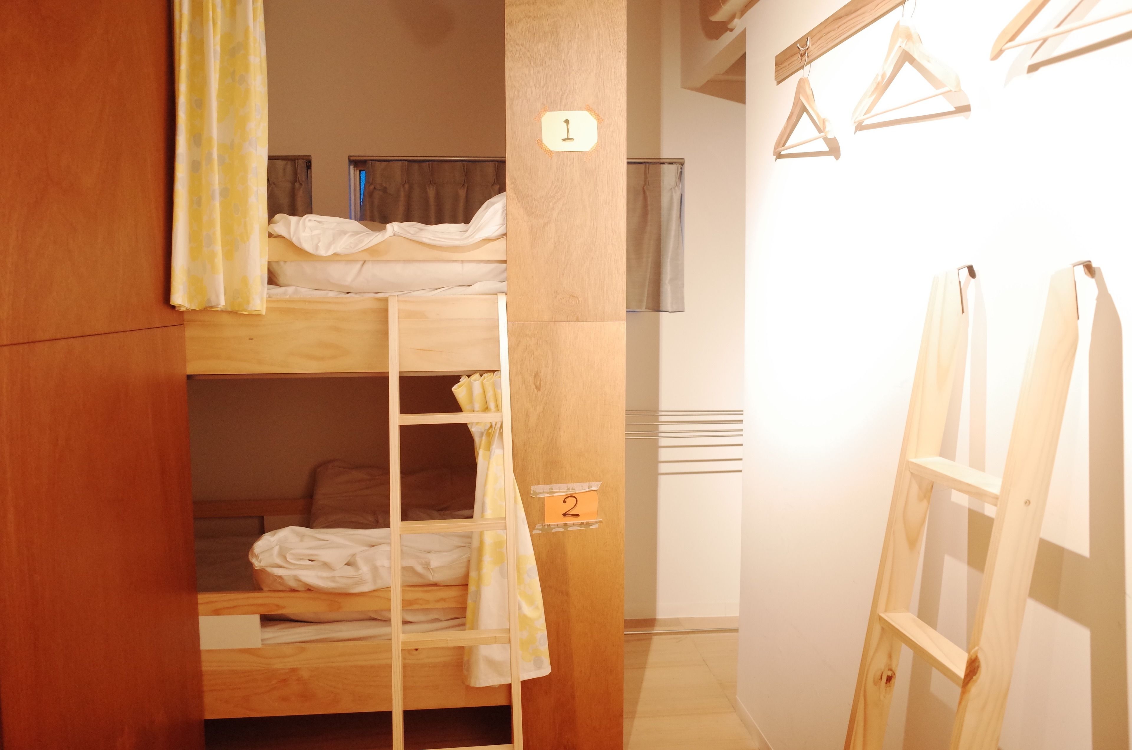 Quarto com beliches, paredes de madeira, camas numeradas e escada de madeira.