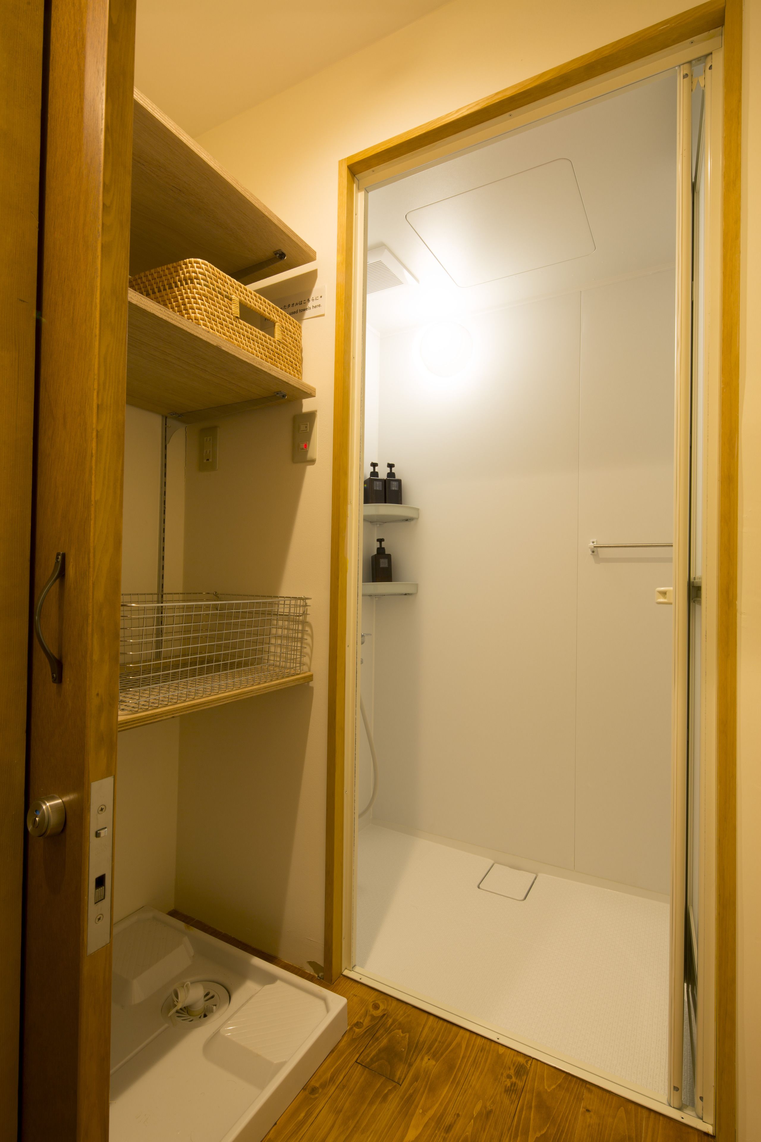 Une salle de bain avec une douche, des toilettes et un lavabo. On peut voir des étagères au-dessus des toilettes et une tringle à rideau de douche.