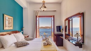 A hotel room with a bed, a TV, a desk, and a view of the sea. - Electra (Syros)