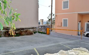 A gated driveway leading to a building with a stone wall and a metal gate. - Electra (Syros)
