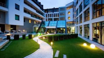 Un edificio moderno con varios pisos, asientos al aire libre y un césped bien cuidado.