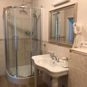 A bathroom with a glass-enclosed shower, a sink, a mirror, and a hairdryer. - Saint Petersburg (Karlovy Vary)
